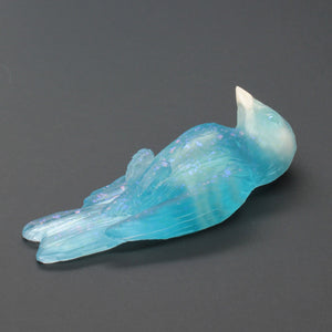 Turquoise bird-shaped object on a gray background